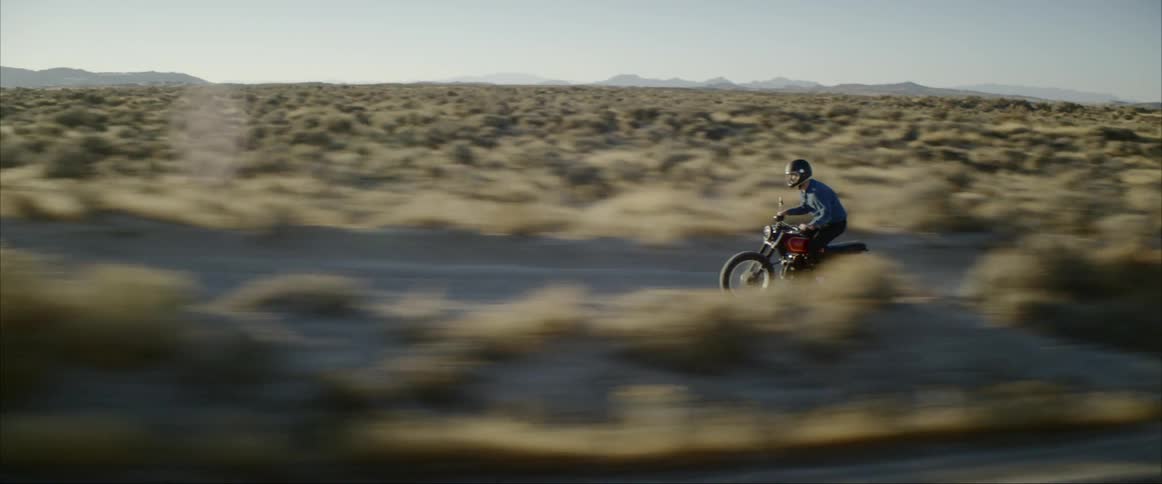 A man is riding a motorcycle in a rural area