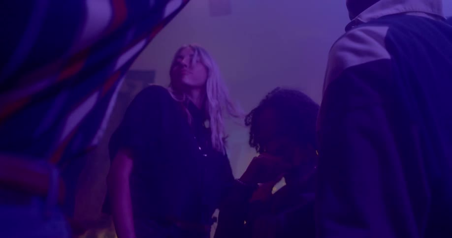 A group of young adults dance as a group in a dimly lit dance club