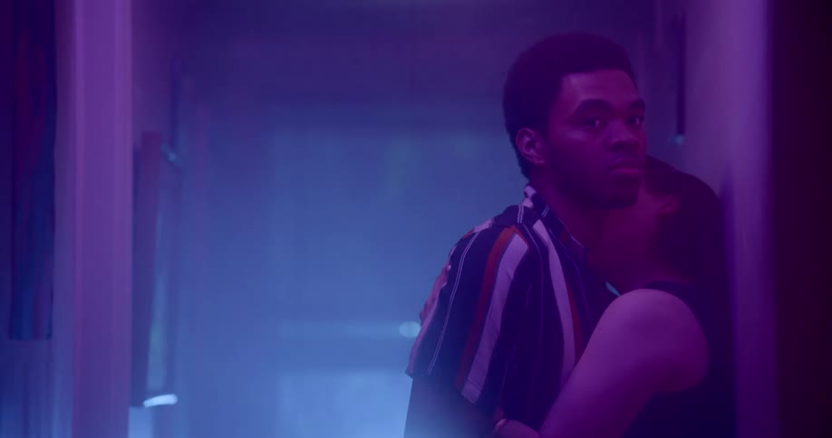 A man and a woman standing in a hallway hugging