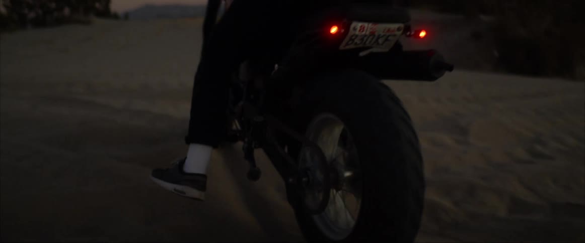The sun sets as a man rides his motorcyle in the desert