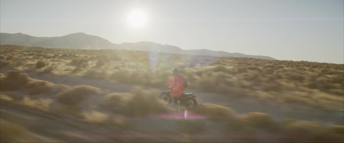 A person rides a motorcycle at high speeds through the desert