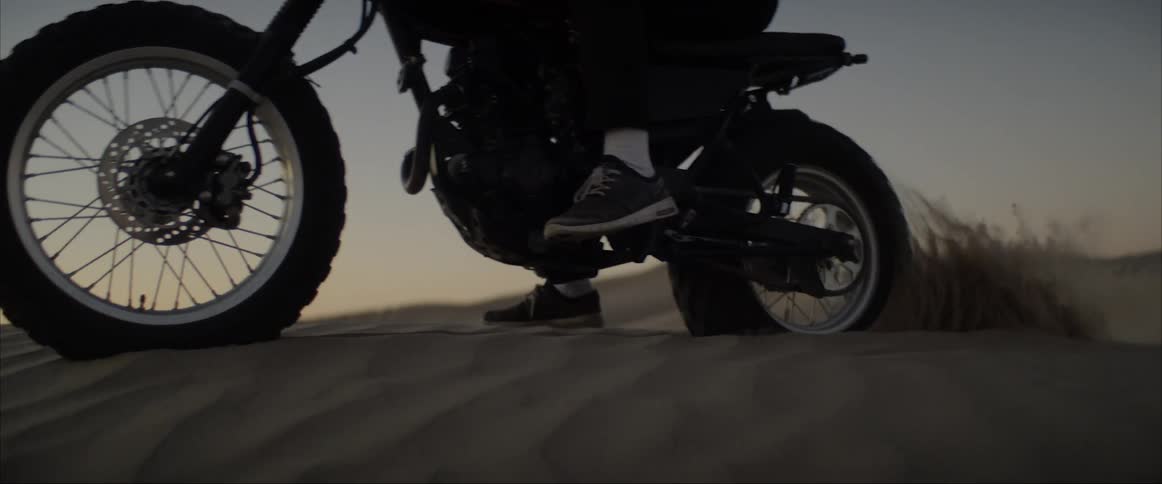 A man is on a motorcycle in a desert area