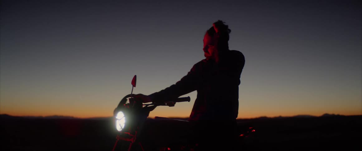 Man sitting on motorcycle at night removes helmet