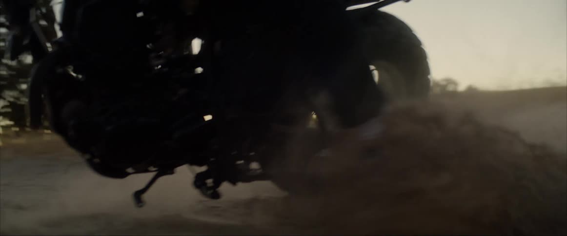 A motorcycle rider makes a sharp turn on a dirt road and puts their leg down to stop from falling