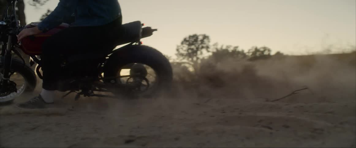 A man drives his motorcycle through the sand