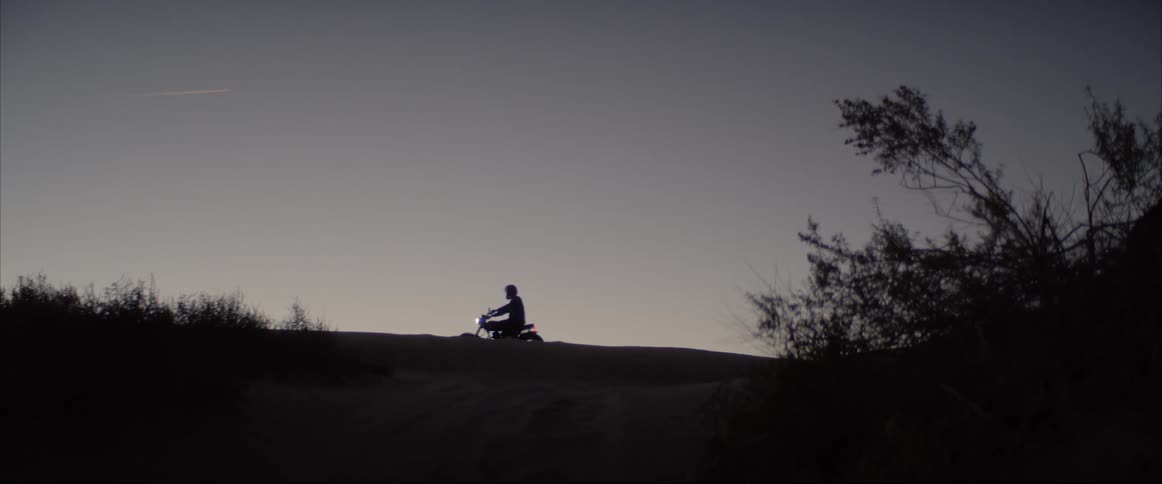 A man is sitting on a motorcycle in the horizon