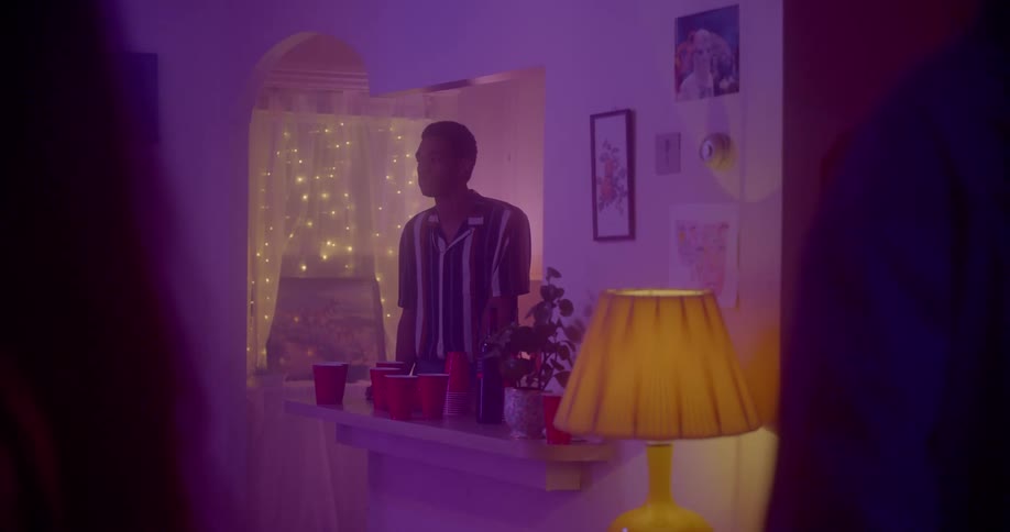 A man stands alone in a room lit in purple
