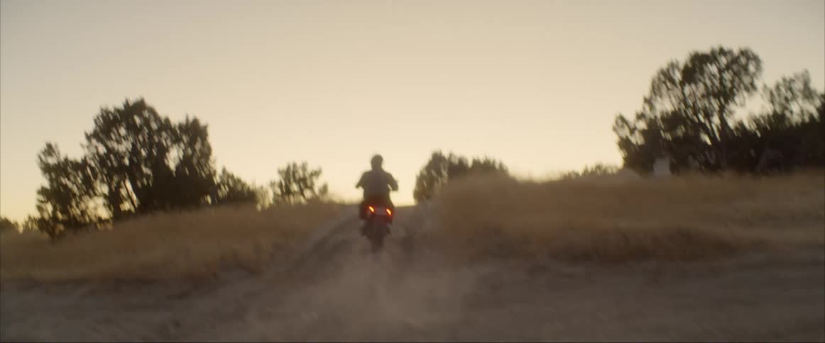 A man is driving a motorcycle on a dirt road