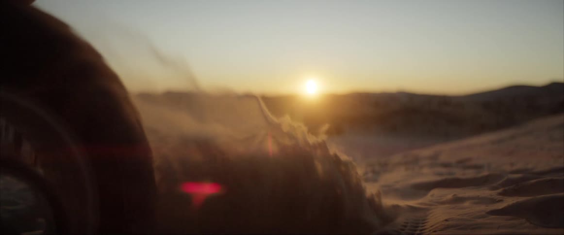A motorcycle wheel turning kicking up sand