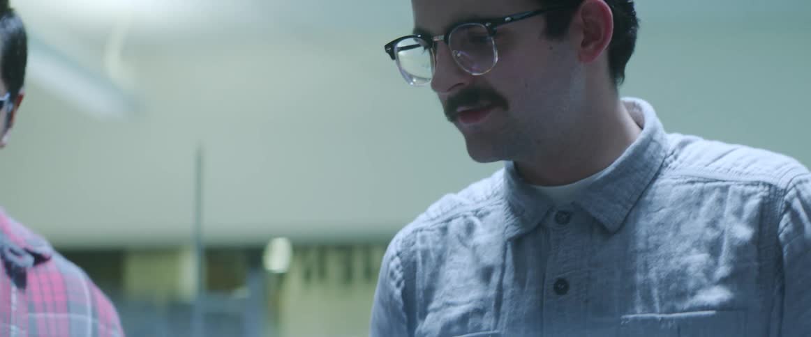 Men contemplate working robotic arm