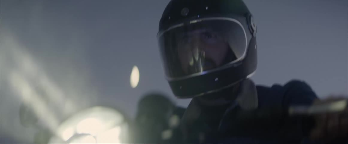 Man wearing a helmet rides a motorcycle in the fog at night