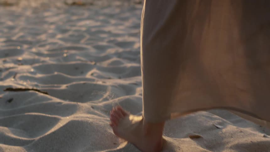 Close up of a woman's feet as she walks through the sand