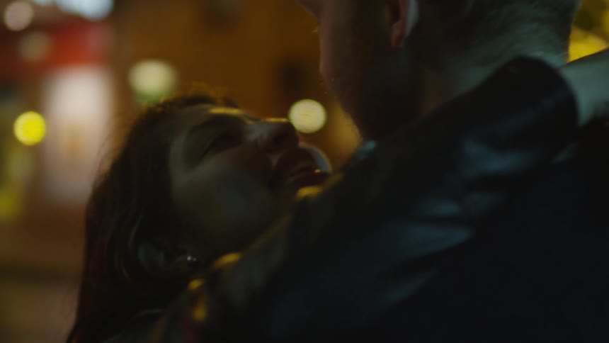 A woman is embracing a man at night in a city