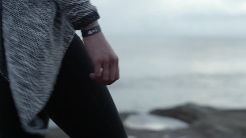 A woman walks along the coast on a cloudy day