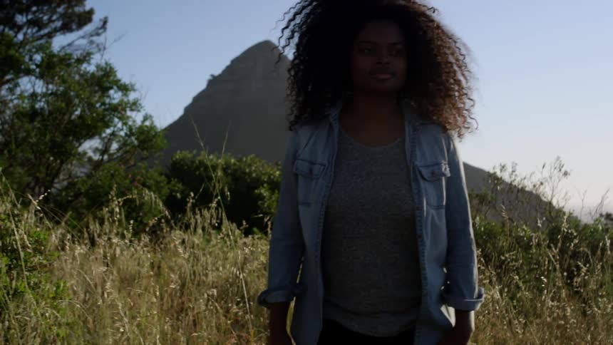A woman in a blue shirt walks through a field