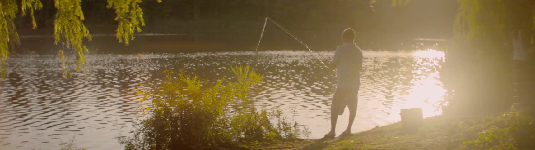 A man stands on the shore and fishes