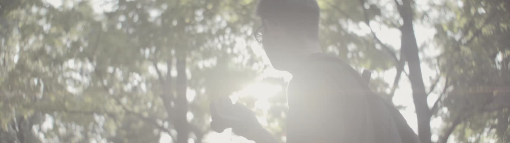 Photographer walking through woods on a bright sunny day