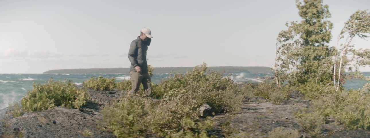 A man walks away from the water as the wind blows
