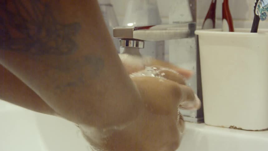 Man washes his hands in bathroom faucet