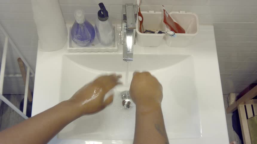 A person washing their hands in a faucet