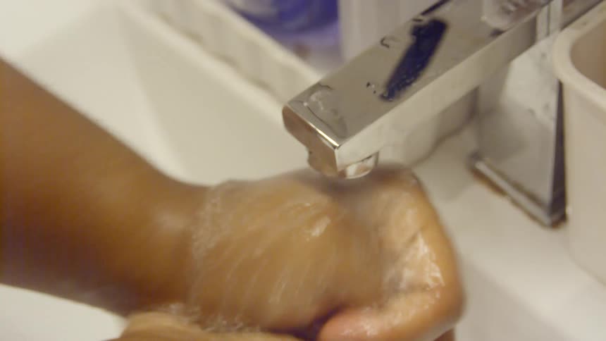 A person washes their hands at the sink