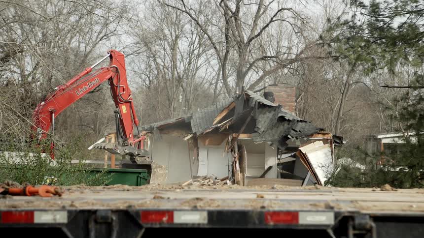 Hydraulic excavator demolishing a house