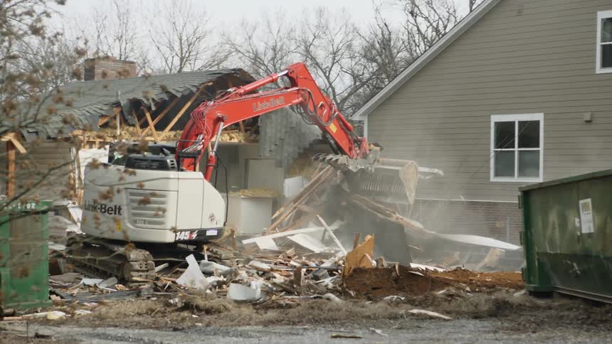 An excavator tears down the wall of a structure