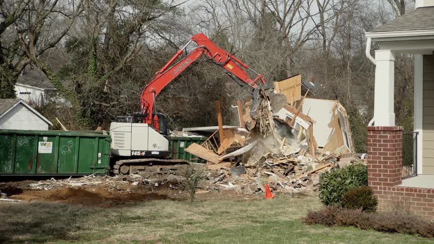 Construction equipment digger lifts debris from demolished building