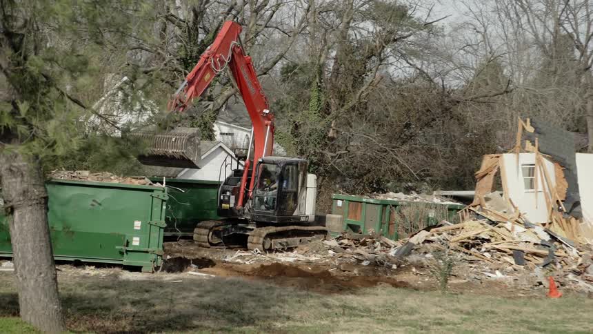 A bulldozer prepares to dump trash in a dumpster