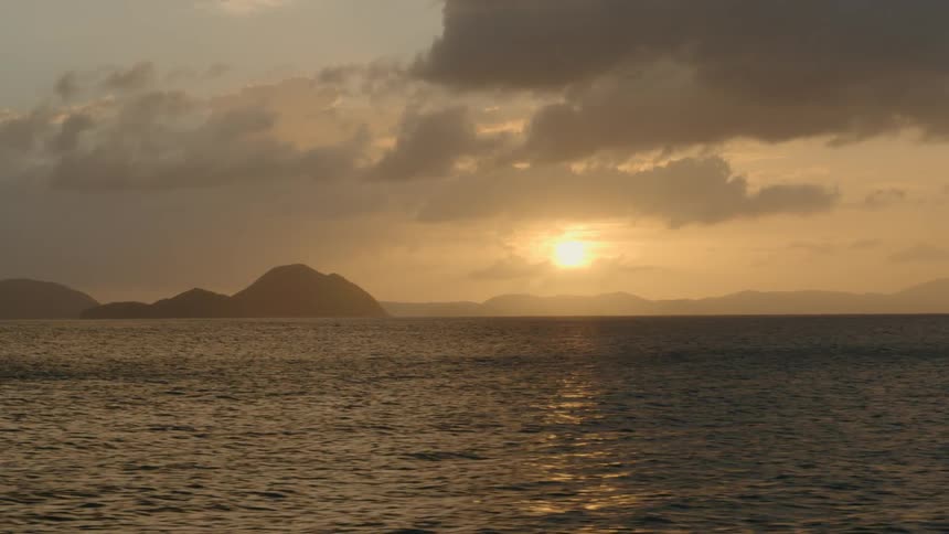 Sunset over the ocean with a coastline in the distance
