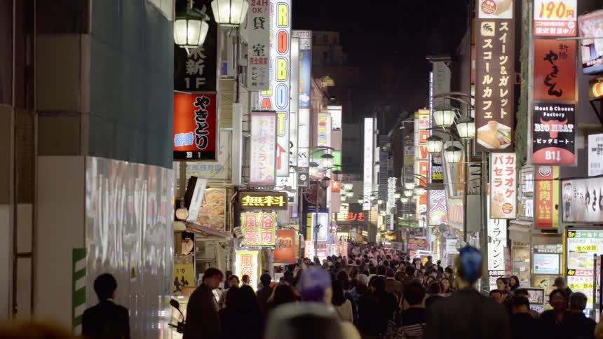 Dolly shot of a Tokyo street crowded with pedestrians at night