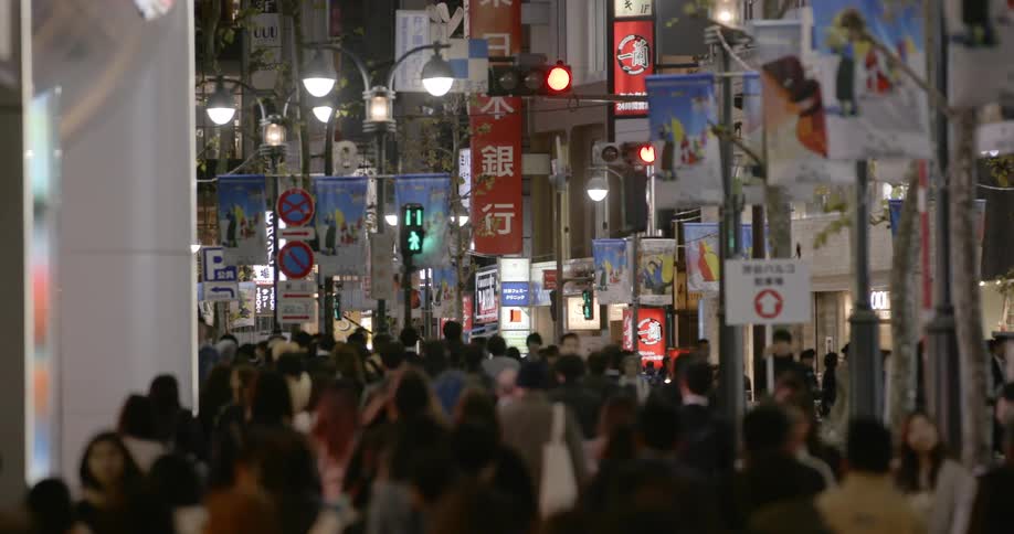 Crowd of people walk on city street sidewalk in Tokyo