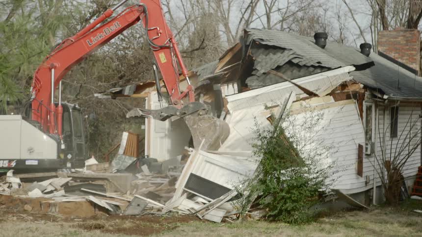 Claw construction equipment demolishes a house