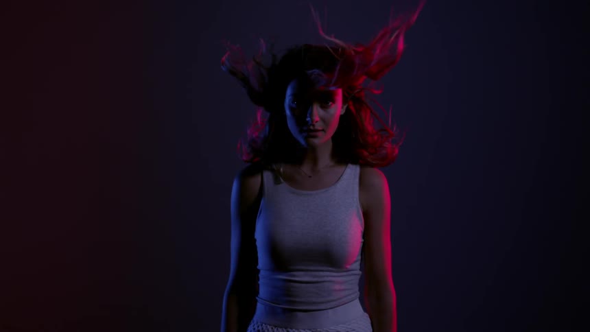 A woman sudden looks up in a dark area while her hair blows around