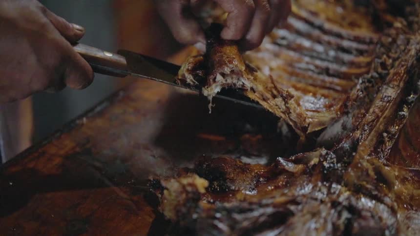 A man slices a rack of ribs