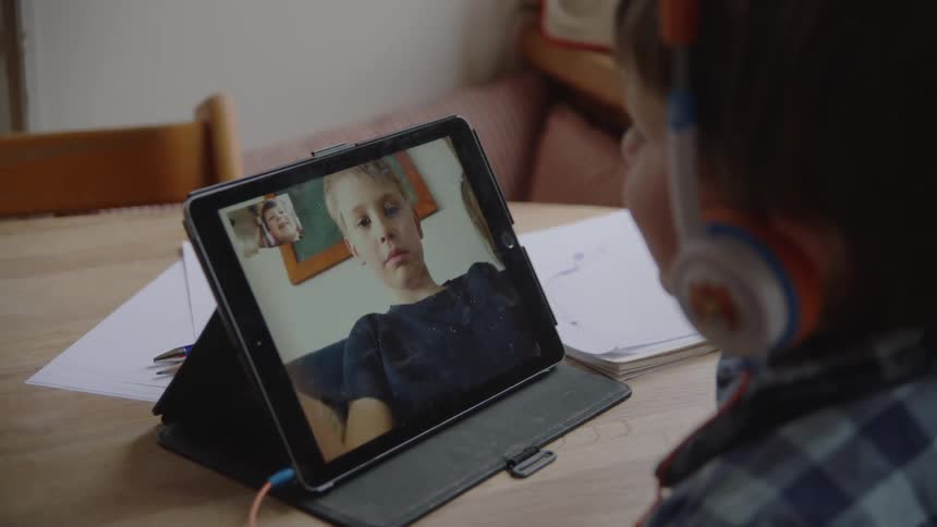 A boy using a tablet to video chat with other boy