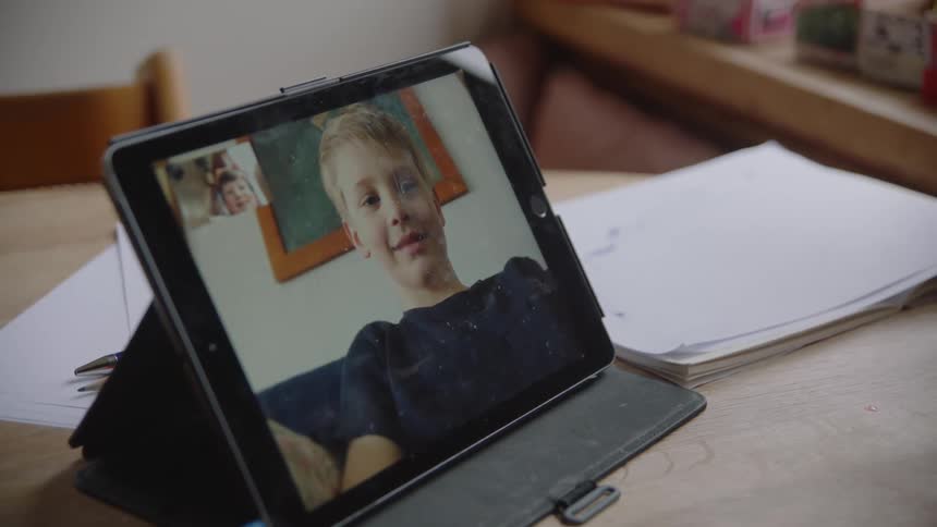 Child skypes on the tablet with his friend in his room