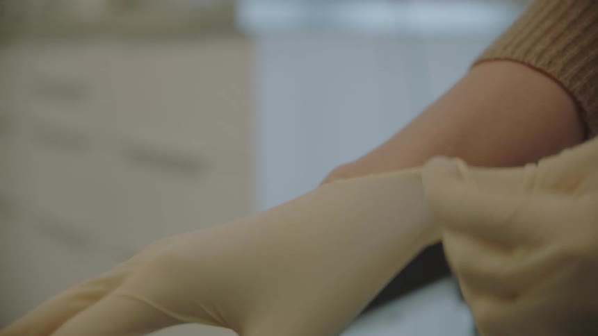 A woman puts rubber gloves on