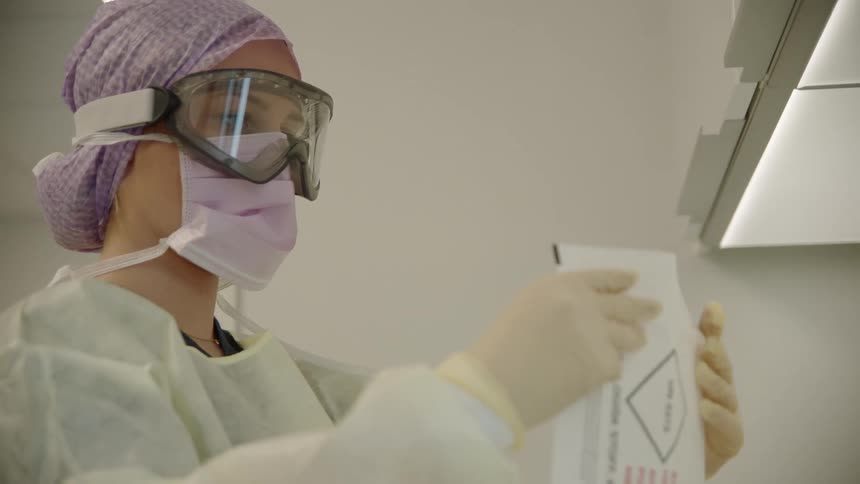 A woman with mask goggles and gloves sealing an envelope