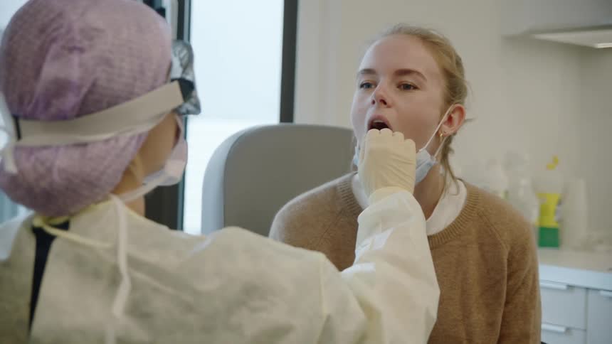 Patient with face mask gets mouth swabbed by nurse