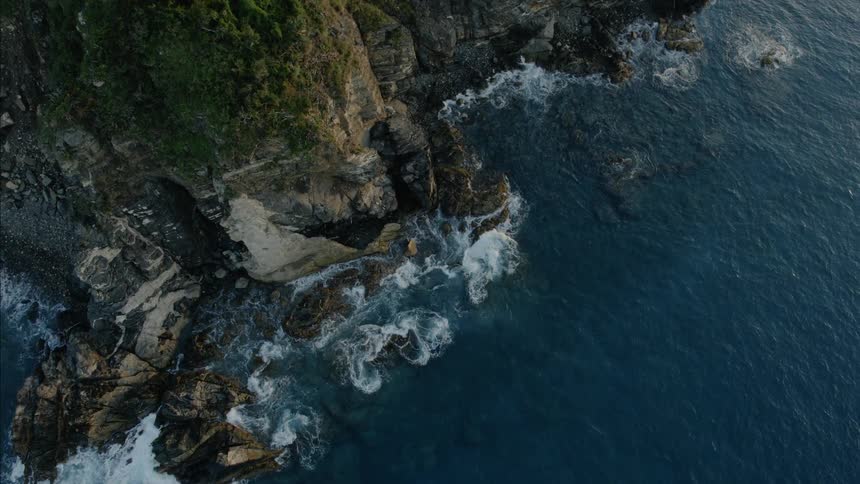 Birds eye view of waves rolling in to rocks along the shore