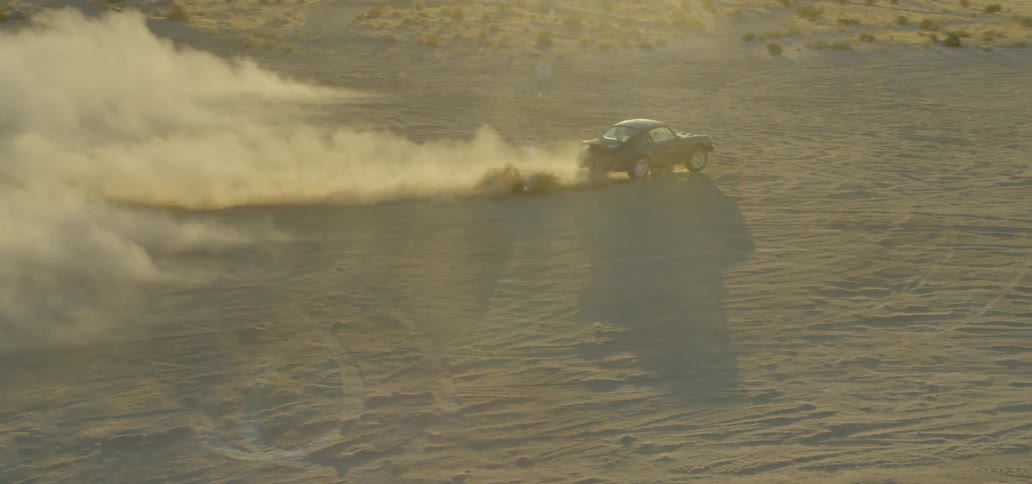 A car leaving a dust cloud behind it as it travels through the desert