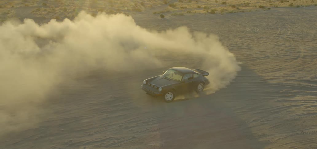 A car drives circles in sand and causes dust