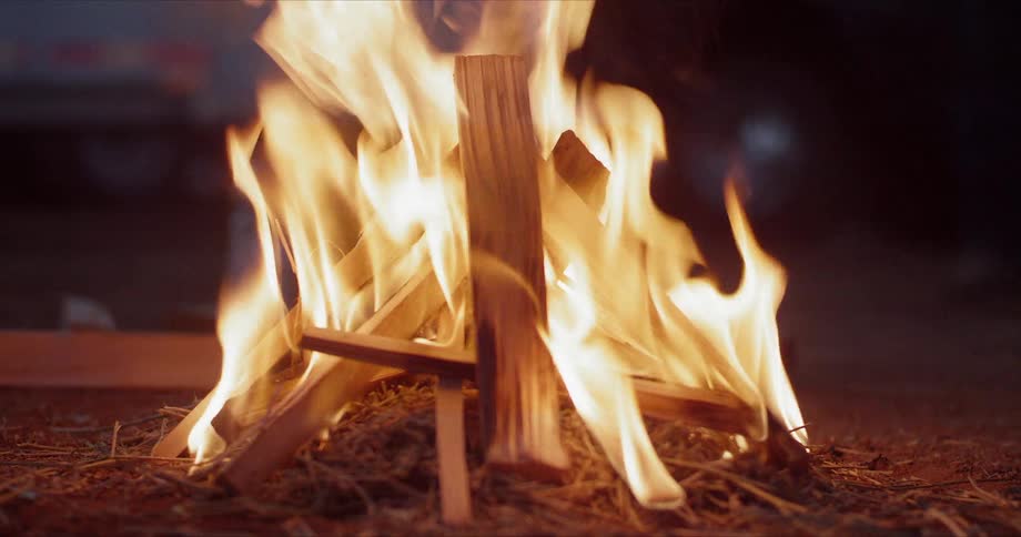 A campfire being lighted outdoors at sunset
