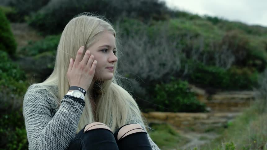 Young woman sitting on the ground looking out