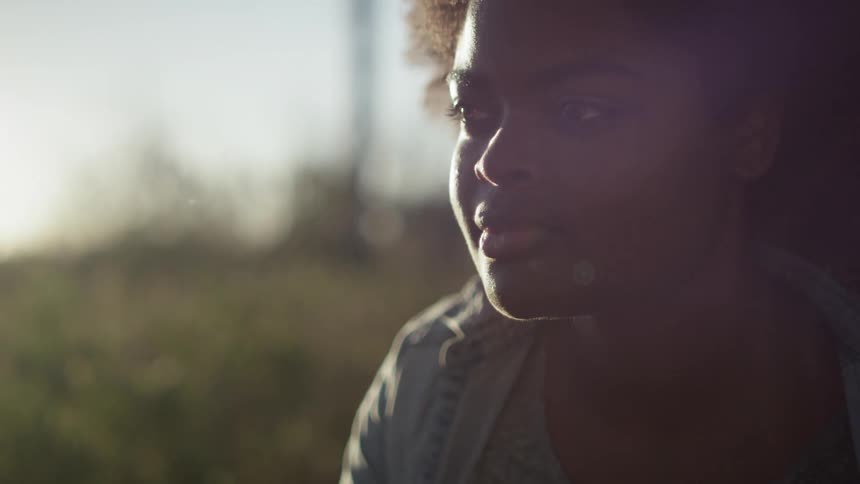 A woman with brown, curly hair looks around outside