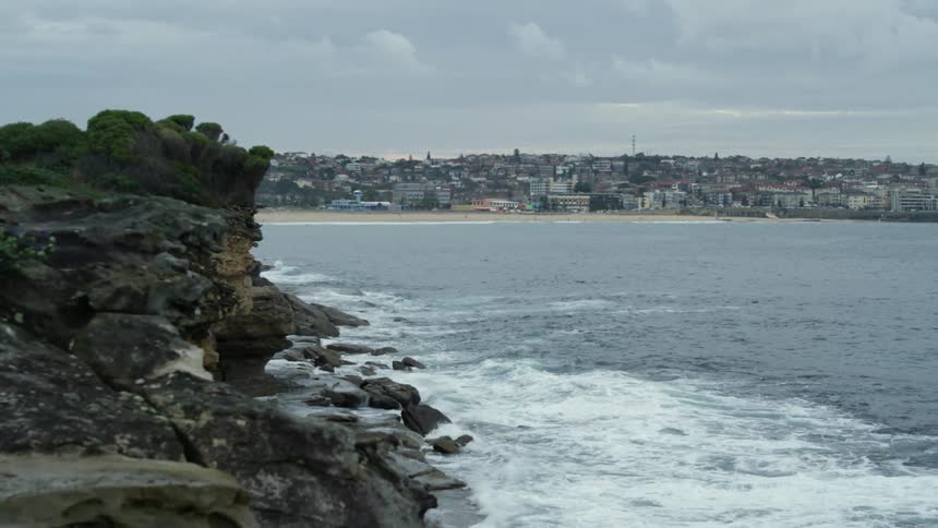 Waves crash against a rocky shore on a cloudy day