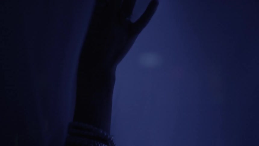 A hand gently touches a curtain waving in a night breeze
