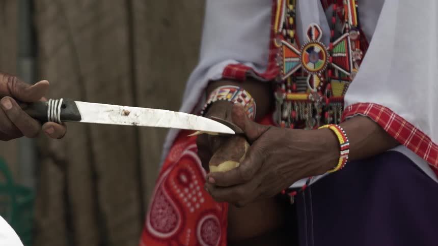 Two people are using a knife to cut something