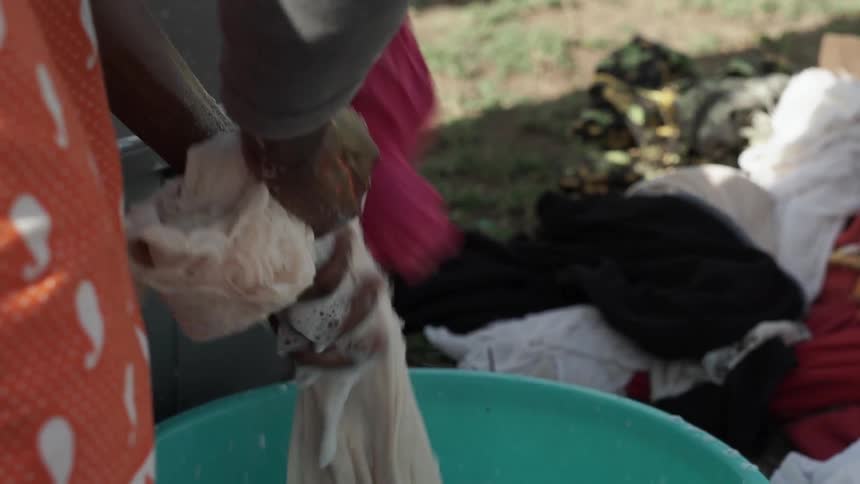 A person washes clothing in a bucket